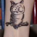caricatura de búho tatuada en brazo