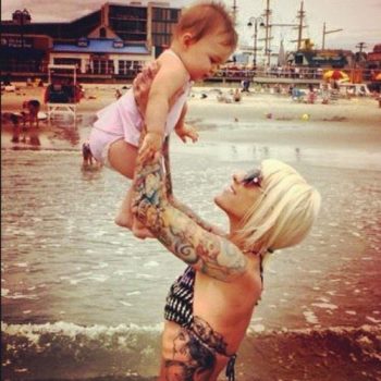 photo of a girl with tattoos holding her baby