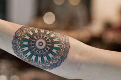 Mándala tatuada en brazo de chica