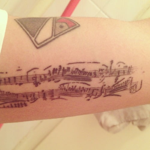 Tatuaje notas musicales en el antebrazo