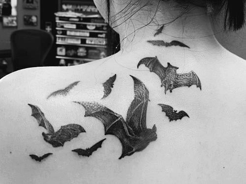 Murciélagos tatuados en la espalda alta de una chica
